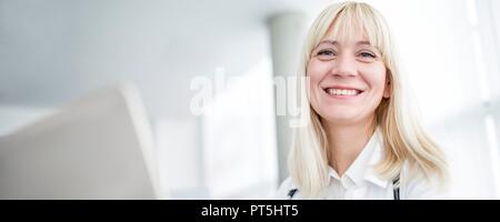 Female doctor using computer and smiling. Stock Photo