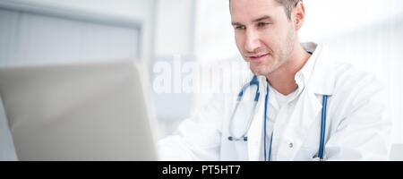 Male doctor using laptop and concentrating. Stock Photo