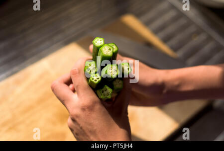 Woman holding ladies fingers vegetables on a cutting board Stock Photo