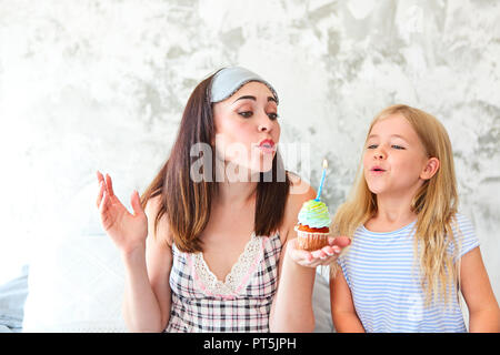 Birthday portrait of the mother and her daughter with cupcake in the morning Stock Photo