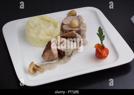 Juicy tenderloin, sprinkled with nut sauce with mushrooms on a plate with mashed potatoes. Stock Photo