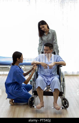 Physical therapist explain treatment method to senior patient and relative Stock Photo