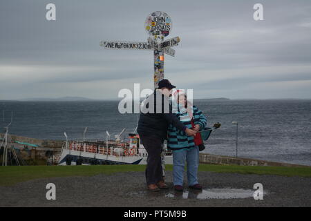 Elderly Tourists holidaymakers taking a selfie photograph under the John O'Groats signpost Caithness Scotland Great Britain UK United Kingdom