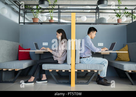 Serious busy young employees working in modern office and analyzing data on laptops while sitting at tables Stock Photo