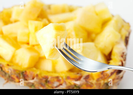piece of pineapple on fork on the background of salad of choped pineapple Stock Photo
