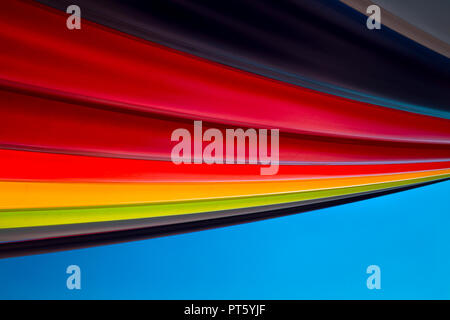 Rainbow colour fabric pieces hung and suspended against the blue sky Stock Photo