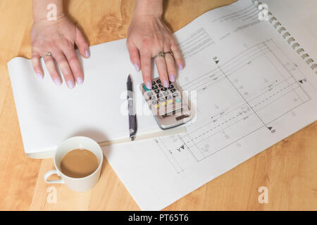 Construction and housing concept. Female hands  working for new project plan lying on the wooden floor. All potential trademarks are removed or intent Stock Photo