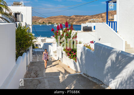 Pretty woman climbing stairs in Greece under a clear blue sky. Serifos island. Stock Photo