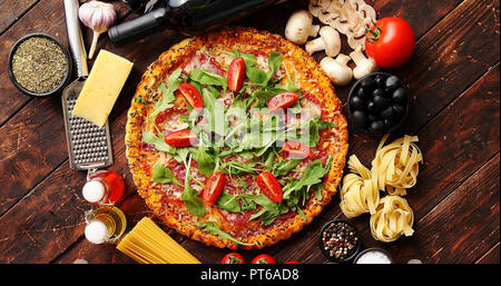 Italian food background with pizza, raw pasta and vegetables on wooden table Stock Photo