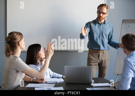 Businesswoman raising hand up at meeting asking team leader ques Stock Photo