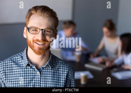 Smiling red-haired millennial business man in glasses looking at Stock Photo