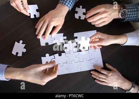 Top close up view of hands engaged in assembling puzzle Stock Photo