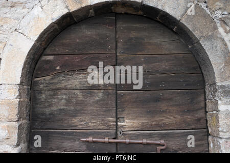 Italy, Varenna, Lake Como, a wooden door with a latch under an arch Stock Photo