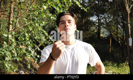 Young angry man in nature, menacing with fist Stock Photo