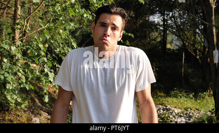 Young sad, disappointed man in nature shrugging Stock Photo