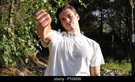 Young man in nature doing thumb down sign Stock Photo