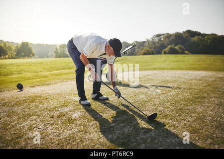 Sporty senior man placing a ball on a tee before playing a round of golf on a sunny day Stock Photo