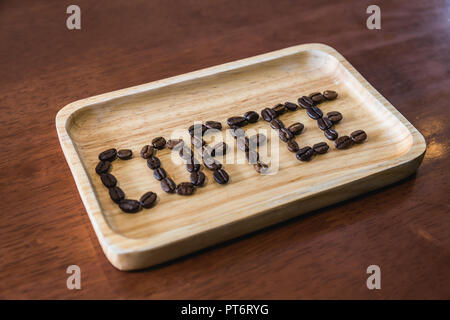 Coffee beans arranged text ' Coffee ' on wooden tray on wood table. Concept idea picture Stock Photo