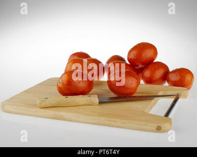 Tomatoes whole and cut  on a wooden cutting board Stock Photo