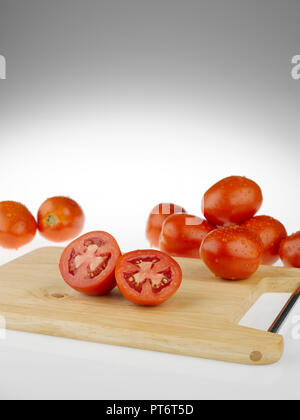 Tomatoes whole and cut  on a wooden cutting board Stock Photo