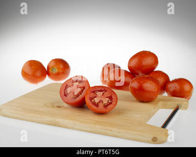 Tomatoes whole and cut  on a wooden cutting board Stock Photo