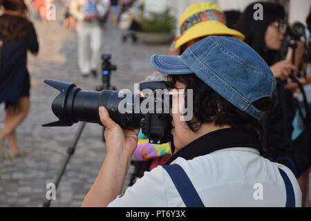 Chinese woman taking photos with her cameras on Tsim Sha Tsui promenade in Hong Kong, China Stock Photo