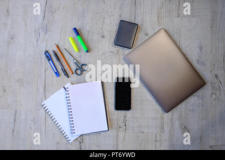 Top view of a project using laptop, hard drive, smartphone, notebooks and writing implements.  Flat lay of   educational and work equipment set on a l Stock Photo