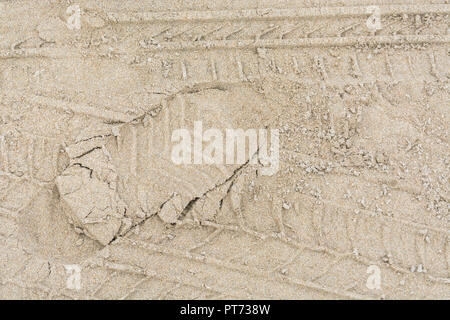 Tyre tracks and footprint in sand. Stock Photo