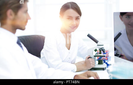 Portrait of confident female scientist with colleague in background at laboratory Stock Photo