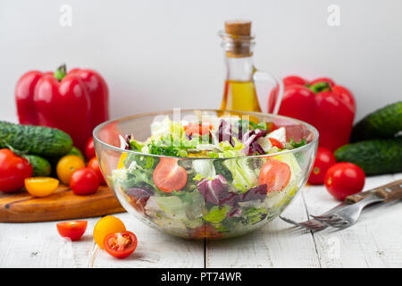 Full bowl of fresh green salad close up on a light table against a white background on a rustic kitchen. Concept helpful and simple food. Stock Photo