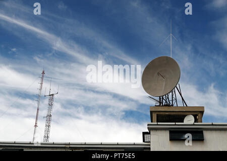 Several kind of communication antennas against deep mountain blue sky with white clouds Stock Photo