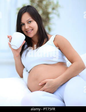 happy pregnant woman drinking milk sitting in the living room. Stock Photo