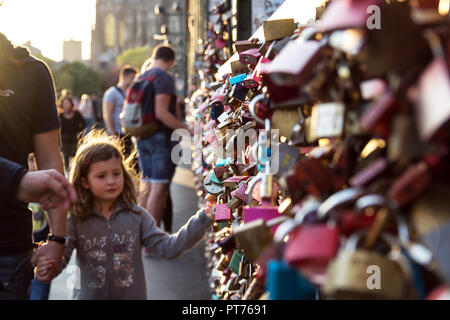 COLOGNE, GERMANY- OCTOBER 06, 2018: tourists on the Hohenzollern bridge are considering locks. The little girl looks at the locks with interest. Stock Photo