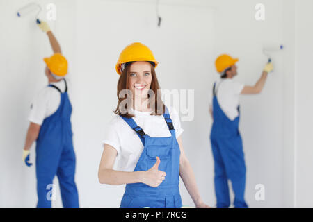 Two young workers in uniform painting the wall Stock Photo