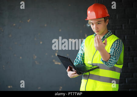 Asian man in protective helmet and construction waistcoat Stock Photo