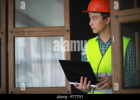 Asian man in protective helmet and construction waistcoat Stock Photo