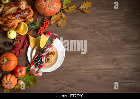 Thanksgiving dinner background with turkey, fall leaves and seasonal autumnal fruits decor around plate, top view. Autumnal festive table setting, cop Stock Photo