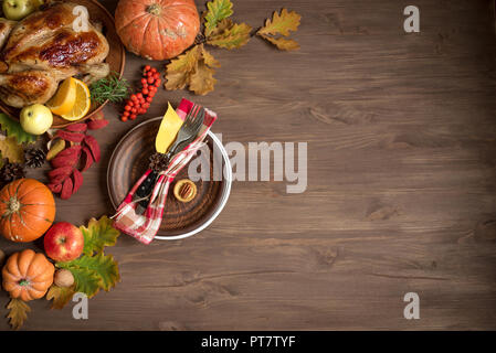 Thanksgiving dinner background with turkey, fall leaves and seasonal autumnal fruits decor around plate, top view. Autumnal festive table setting, cop Stock Photo