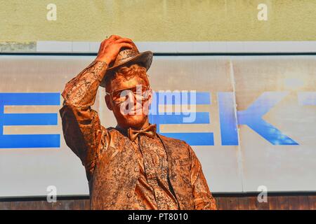 HUSTOPECE, CZECH REPUBLIC - OCTOBER 7, 2018: Cupreous painted artist like living statue dressed like gentleman. Living statue of serious man.  Living  Stock Photo