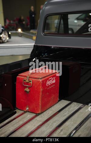 Antique rusted, red, Coca Cola (R) cooler in the bed of a black pickup truck. Stock Photo