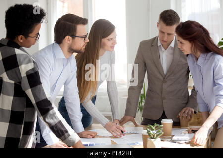 Team working standing looking at documents in office Stock Photo