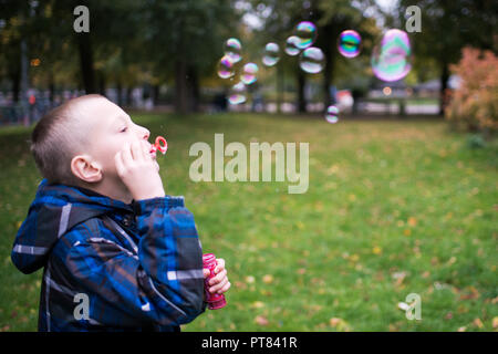 Seven year old boy blowing soap bubbles on a meadow Stock Photo