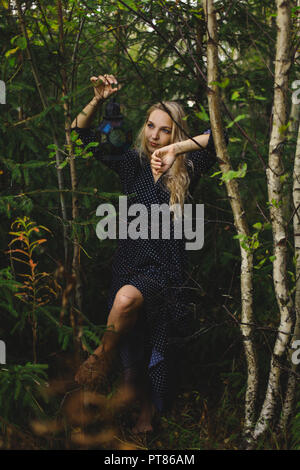 blonde in the forest. In the hands of a girl holding a vintage lantern Stock Photo