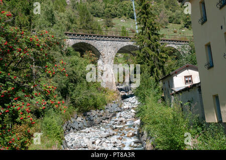 Arched stone train bridge over a stream in Lavin is a municipality in the district of Inn in the Swiss canton of Graubünden Stock Photo