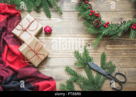 Christmas composition of wreath, gifts, checkered pleid on wooden board. Flat lay. Top view. Copy space. Stock Photo