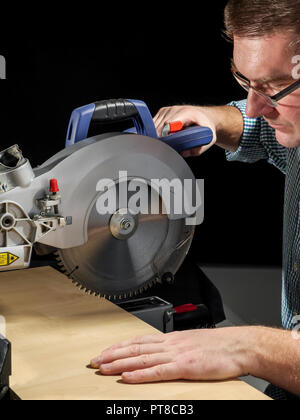 Carpenter cutting flaxboard using sliding compound mitre saw Stock Photo