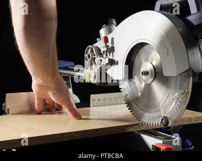 Carpenter cutting flaxboard using sliding compound mitre saw Stock Photo