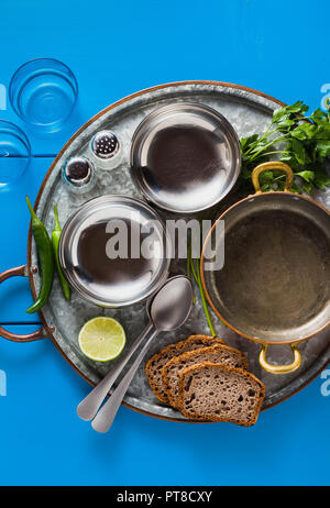 https://l450v.alamy.com/450v/pt8cxy/table-served-in-indian-style-tin-tray-with-copper-pan-and-empty-metal-bowls-plate-on-a-blue-wooden-table-copy-space-pt8cxy.jpg