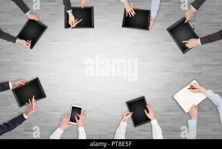 Group of people with devices in hands having desk discussion and making reports together on laptop, tablet, notebook  Stock Photo