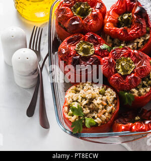 ready baked stuffed peppers in a glass baking dish on white marble table. healthy vegan cuisine for the whole family. comfort food Stock Photo